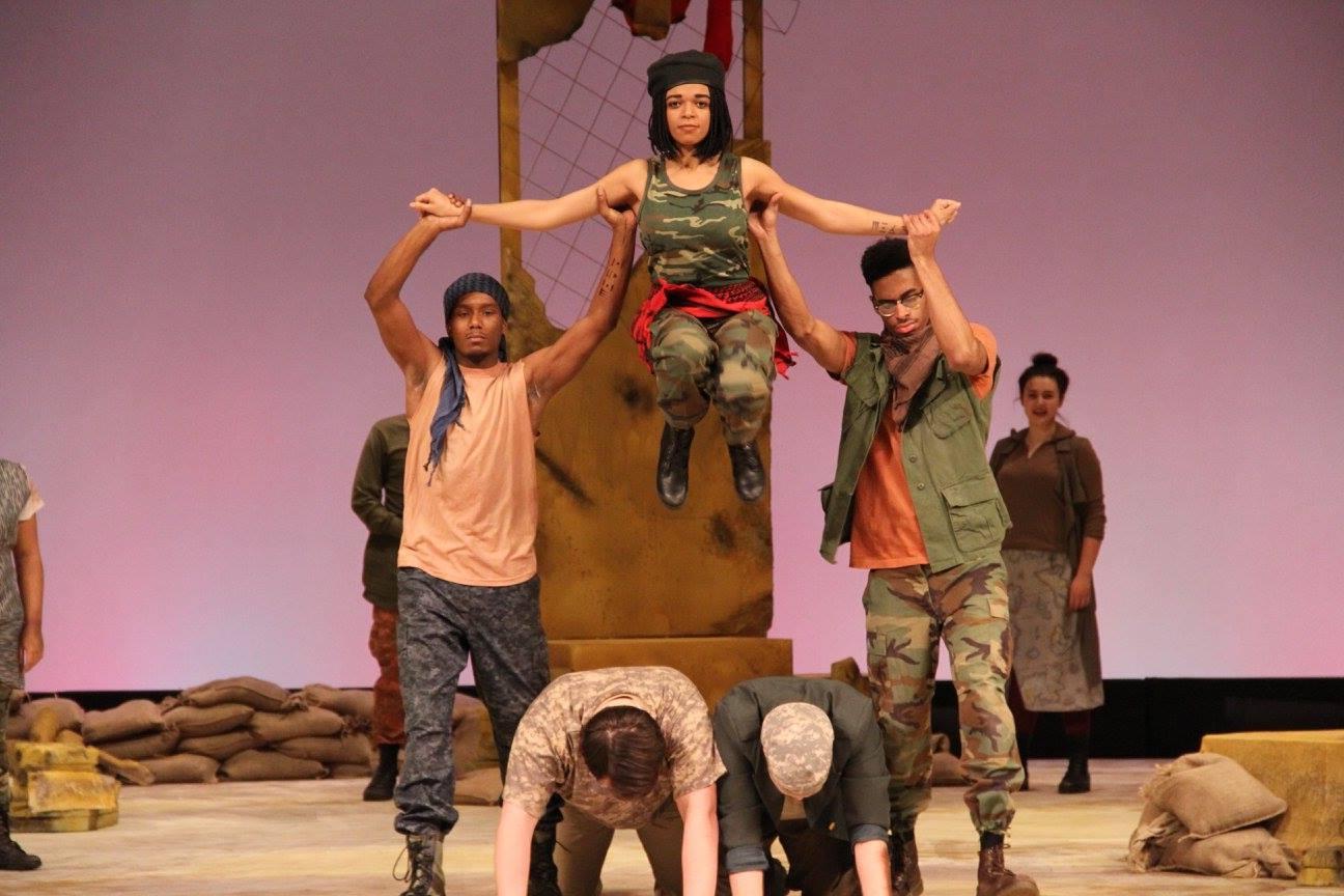 Two male students holding up a female student by her arms