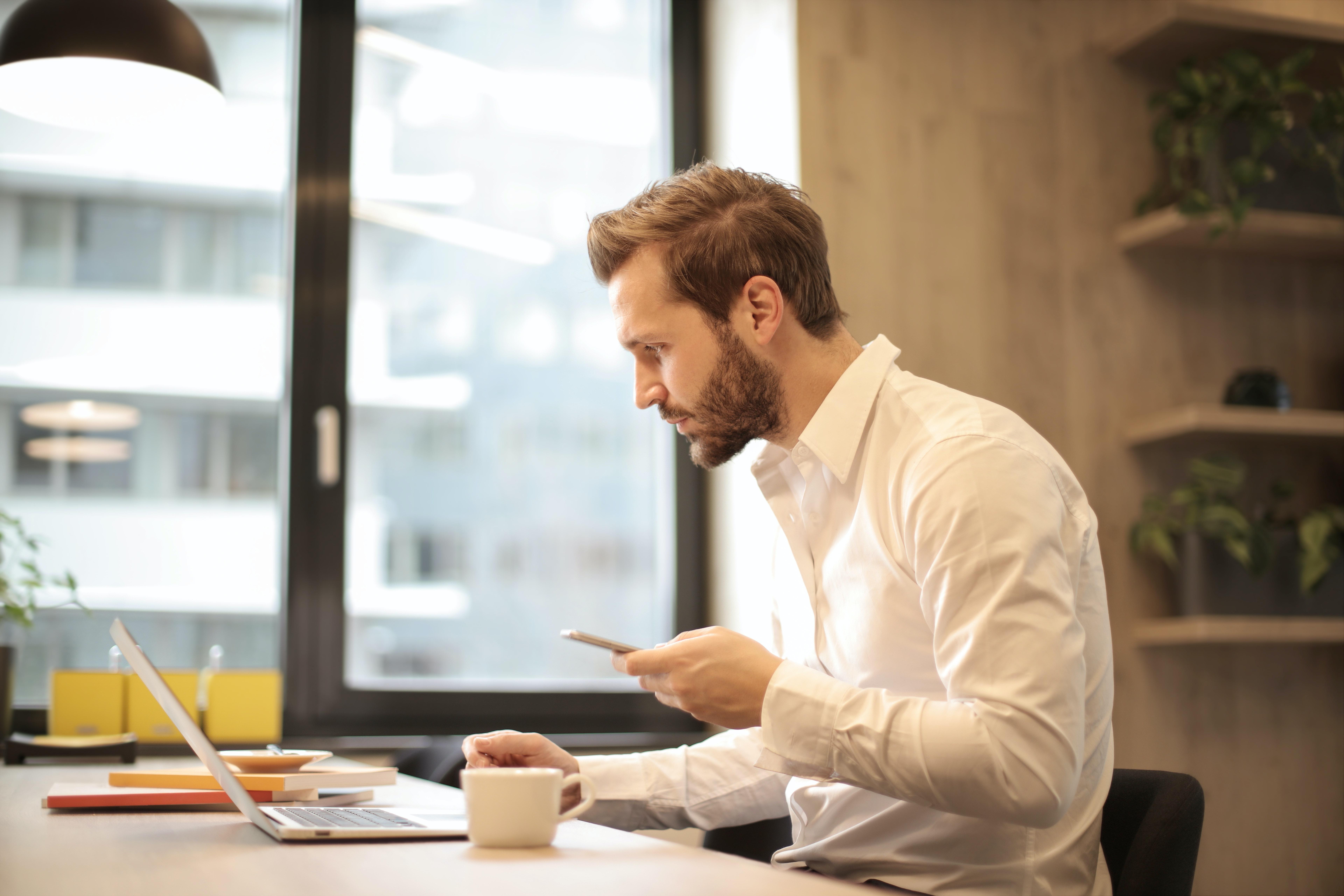 A business man drinking coffee while working at his laptop