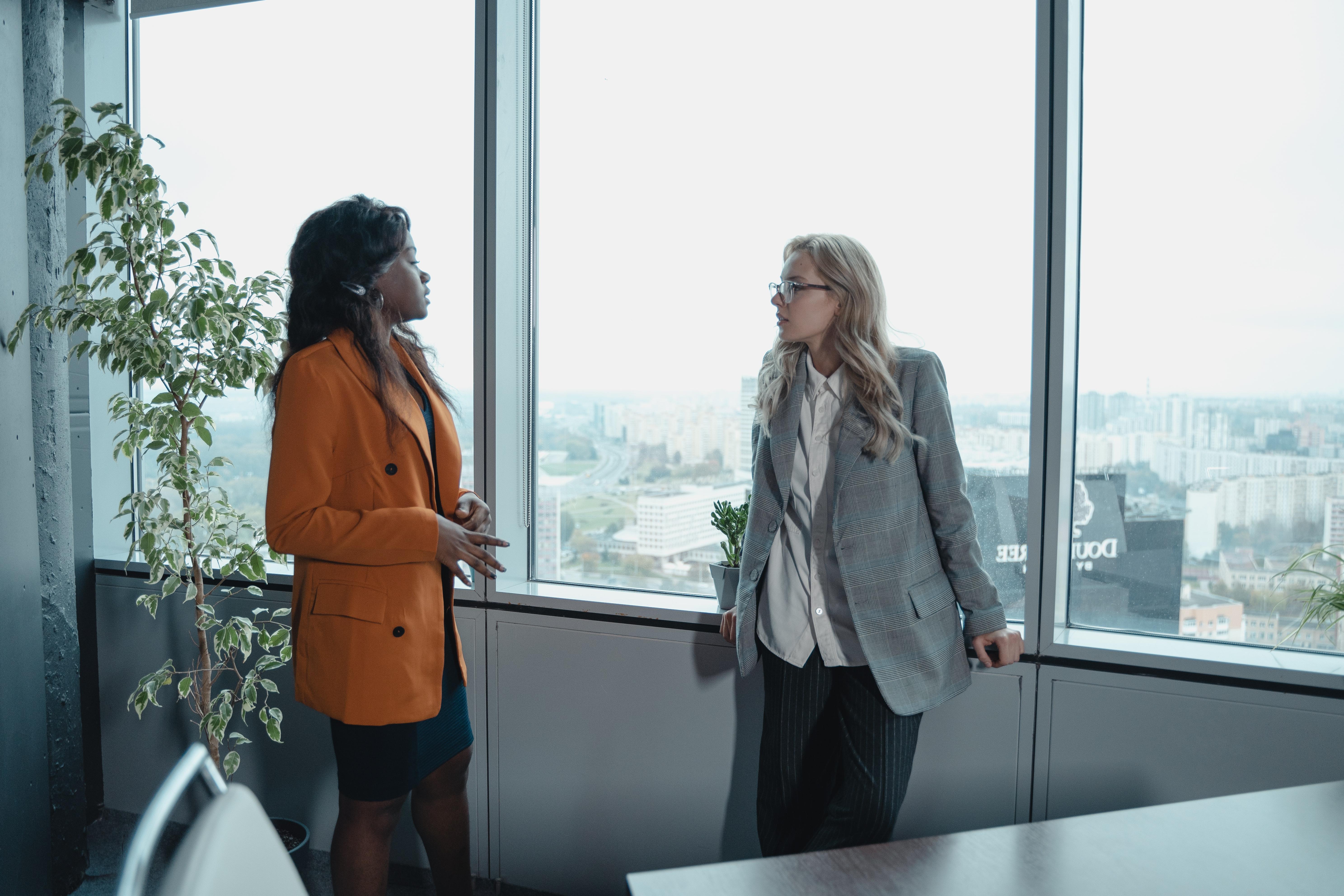 Two business women talking next to a window